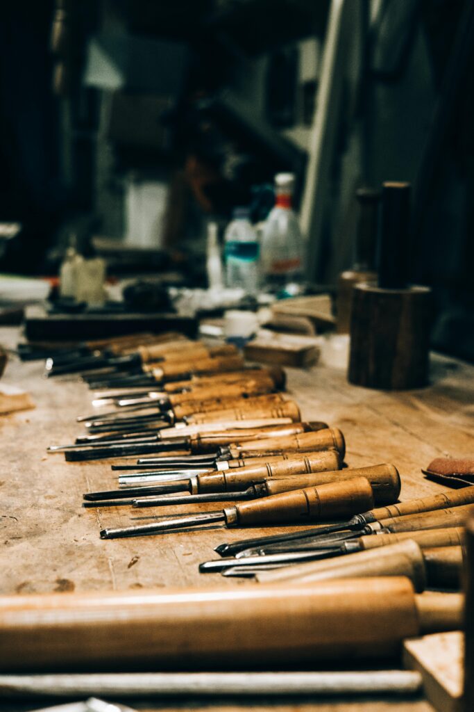 A collection of chisels neatly arranged on a wooden workbench in a workshop setting.